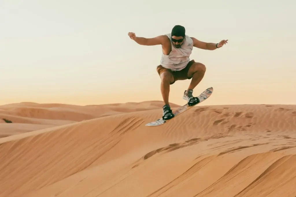 Sandboarder descending massive dune while sandboarding Namibia